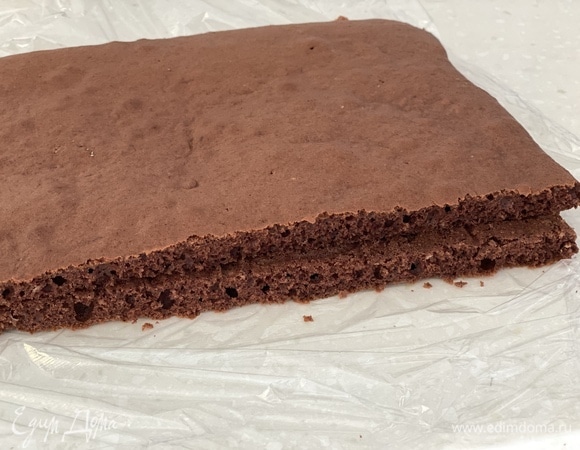 Противень застелить пергаментом. Вылить тесто, аккуратно распределить. Выпекать при 180°C около 10 минут. Остудить, перевернуть и снять бумагу. Разрезать бисквит на 2 части.