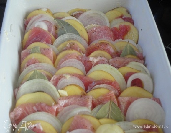 Форму для запекания смазываем сливочным маслом. От себя я один зубчик чеснока порубила ножом и натерла им дно формы. Выкладываем «чешуйкой» картофель, мясо, лук. Ну и лавровый лист кое-где втыкаем :) Выливаем горячую воду. Можно сверху сбрызнуть оливковым маслом.