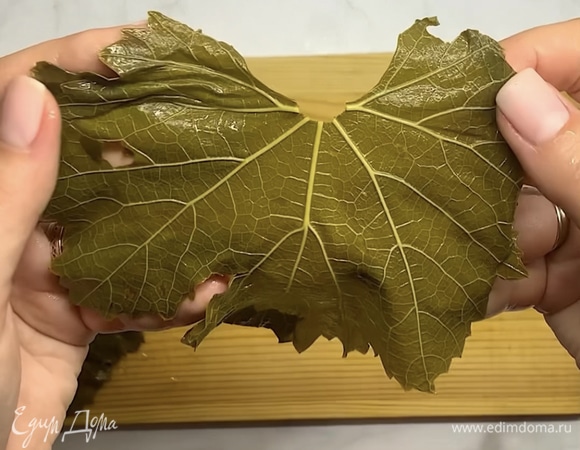 Виноградные листья промываем, отрезаем у каждого листика веточку. Рваные или не очень красивые листики выкладываем на дно кастрюли.