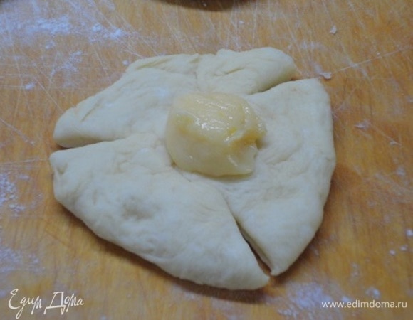 Подошедшее тесто разделите на 15 кусочков (примерно по 65 г). Руками сформируйте из каждого кусочка небольшую лепешку. Сделайте 3 надреза, а на середину выложите 1 ч. л. лимонного крема.