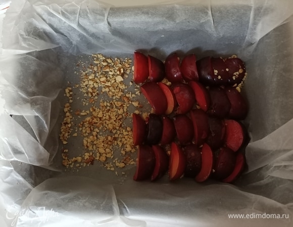 Форму застилаем пергаментной бумагой. Затем выкладываем орехи, а сверху — нарезанные дольками сливы кожурой вверх.