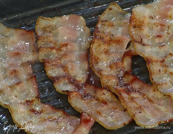 Разогреть сухую сковороду-гриль и обжарить бекон с двух сторон, затем выложить на бумажное полотенце, чтобы удалить лишний жир.