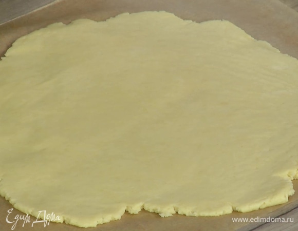 Поместить тесто между двумя листами бумаги для выпечки и раскатать в пласт толщиной в полсантиметра.