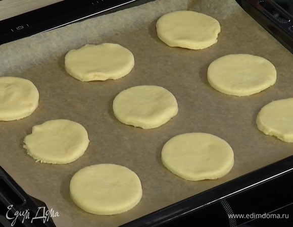 Вырезать из теста небольшие кружки, выложить на застеленный бумагой для выпечки противень и выпекать в разогретой духовке 8–10 минут, затем остудить.