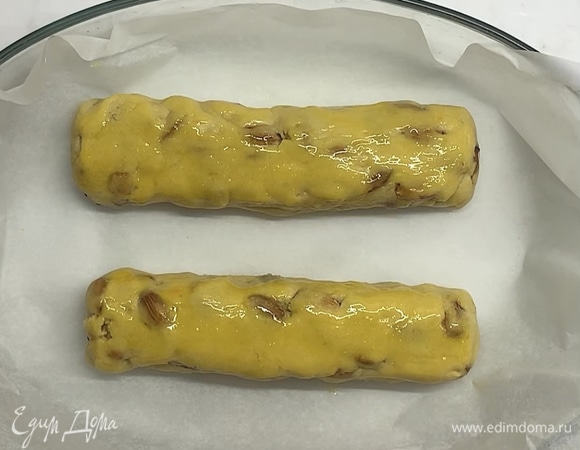Затем делим на 2 части и формируем колбаски. Сверху смазываем желтком и перекладываем в форму или на противень, застеленный бумагой для выпекания. Отправляем в заранее разогретую до 180°C духовку на 25–30 минут.
