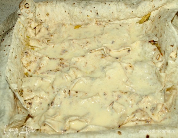 Выкладываем часть начинки. Сверху на начинку выкладываем смоченные в приготовленной смеси нарезанные кусочки лаваша. Кусочки хорошо смачиваем, выкладываем все. Закрываем одним пластом лаваша начинку и смоченный лаваш. Смазываем пласт кефирной смесью.
