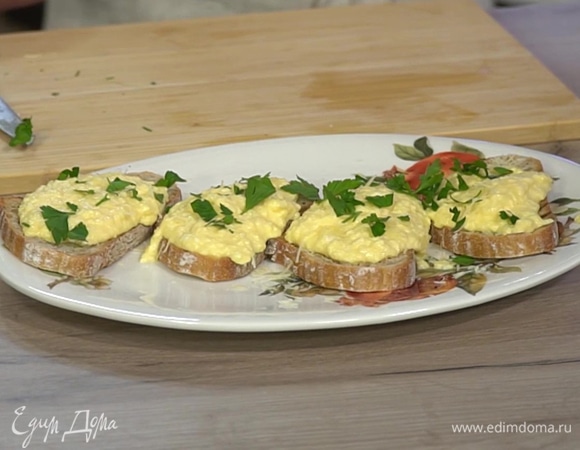На большую тарелку выложить кусочки хлеба, смазать их оставшимся сливочным маслом, разложить обжаренные яйца, затем посыпать пармезаном и листьями петрушки.