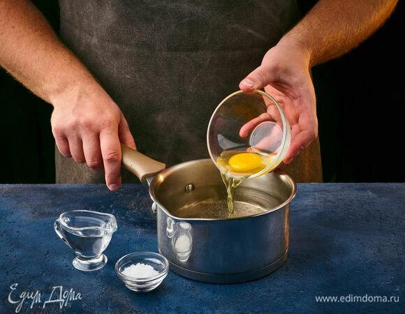 Сварите яйцо пашот. Сотейник наполните водой, добавьте уксус и соль, перемешайте. Яйцо заранее аккуратно разбейте в маленькую миску. Воду доведите до кипения, сделайте средний огонь. При помощи венчика закрутите воронку и быстро, но осторожно опустите яйцо в центр этой воронки. Варите 2 минуты.