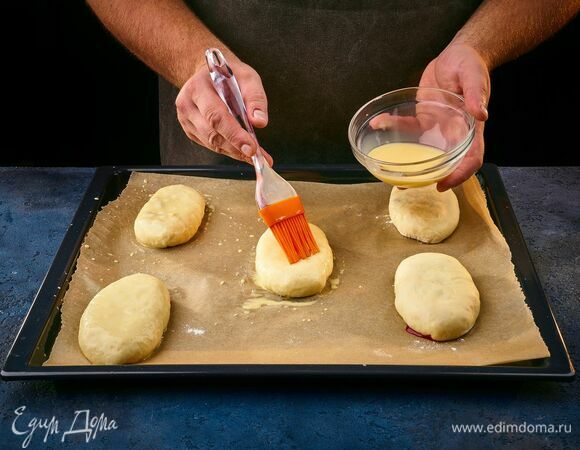Желток взбейте с молоком. Смажьте пирожки с помощью кисточки. <br />
Выпекайте в разогретой до 180°C духовке 15–20 минут.