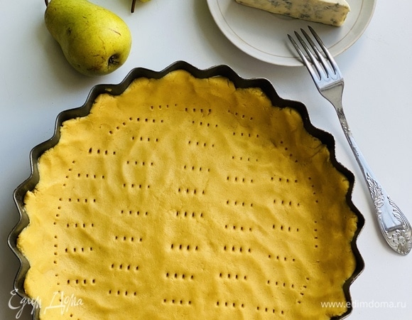 Распределить тесто по форме (20 см), наколоть вилкой, выложить грушу, залить заливкой (для которой смешать яйца с молоком) и покрошить сверху сыр.