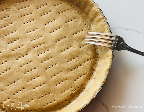 По истечении этого времени тесто раскатать под форму (26 см), переложить его и наколоть вилкой. В таком виде убрать на 15 мин. в морозилку.