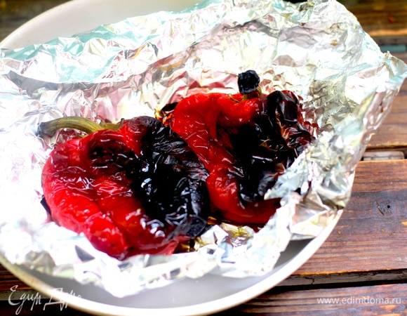 Духовку разогреть до 200°C, выложить на фольгу перцы, запечь до черных подпалин. Вынуть, сложить в пакет, завязать и дать остыть.