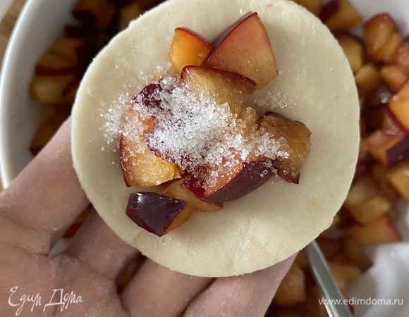 В это время подготовить начинку. Сливу очистить от косточек, нарезать мелкими кубиками. Раскатать тонко тесто, вырезать стаканом кружки, положить в центр сливу, насыпать сверху чуть сахара и защипать края.