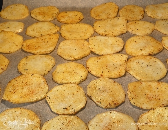 Духовку разогреть до 220–230°C. Противень застелить пергаментом, разложить картофель в один слой и запекать около 10 минут.