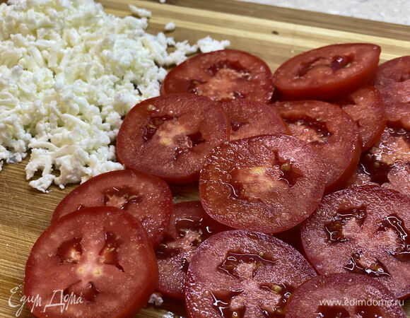 Натрите на терке моцареллу и нарежьте помидоры кружочками. Если помидоры неспелые, присыпьте их щепоткой сахара. 