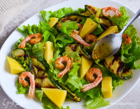 На блюдо выкладываем листья салата, креветки, цукини и манго. Поливаем заправкой.
