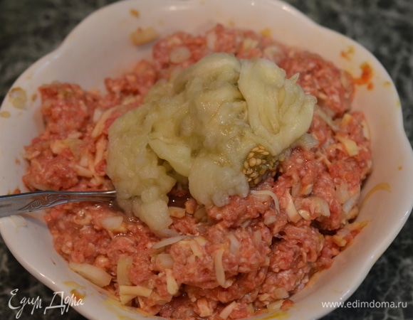 Баклажан разрежьте пополам и выскребите ложкой мякоть. Добавьте ее также в фарш. Перемешайте.