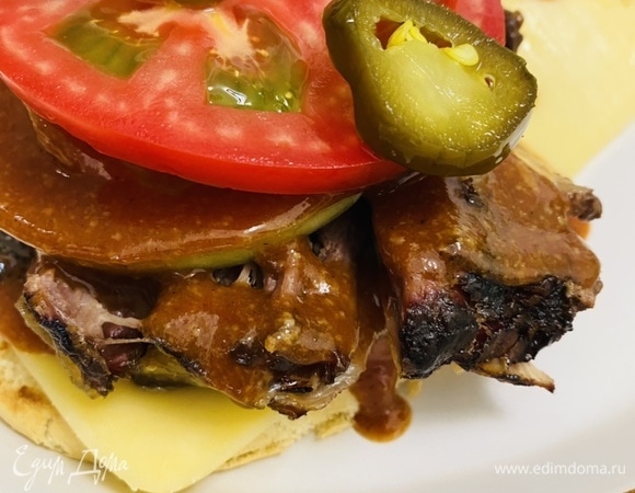 На мясо выложить кольца лука (лук по желанию можно заранее замариновать), помидор и нарезанные кружочки маринованного халапеньо.