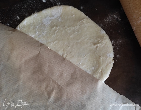 Достаем наше тесто. Делим на 2 части. Я раскатываю сразу на тефлоновом коврике (пергаменте). Если оно прилипает к скалке, немного припылите мукой и раскатайте через лист пергамента в круг диаметром примерно 30 см.