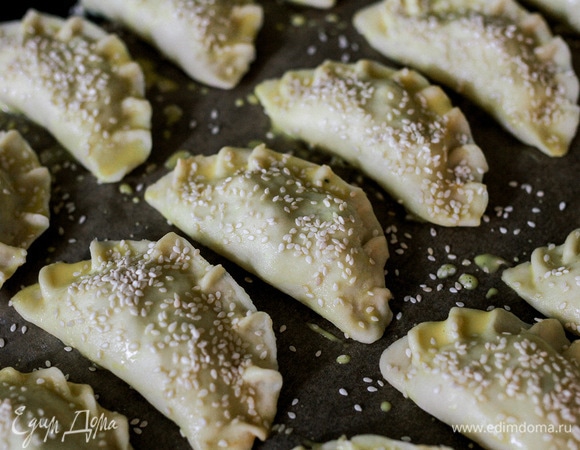 На половину теста выложить начинку и залепить пирожок по принципу вареника. Смазать желтком и посыпать кунжутом.