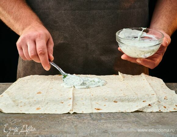 Расправьте лаваш, распределите по нему сметанный соус.