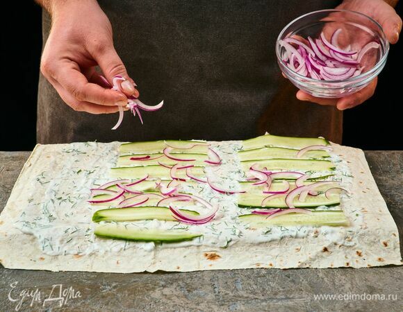 Выложите маринованный лук и ломтики огурцов.