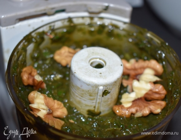 Теперь добавьте грецкие орехи и предварительно очищенный и разрезанный пополам чеснок.