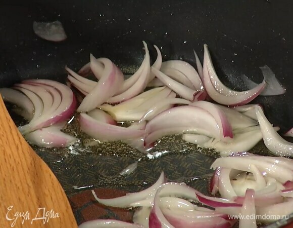 Красный лук почистить и нарезать тонкими дольками, затем разогреть в сковороде оливковое масло и обжарить лук до золотистого цвета.