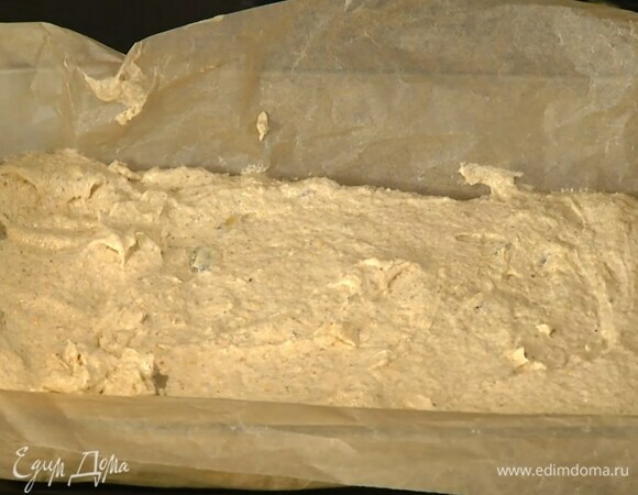 Форму для выпечки выстелить пищевой бумагой, выложить тесто и разровнять его.