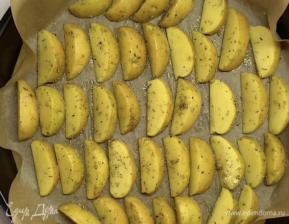 Выкладываем картофельные дольки на застеленный пергаментом противень. Ставим в заранее разогретую духовку на 20–25 минут при 180°C.