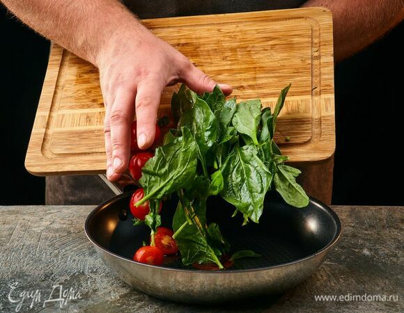 Обжарьте шпинат в оливковом масле с измельченным зубчиком чеснока. Добавьте помидоры черри, разрезанные пополам, посолите и поперчите.