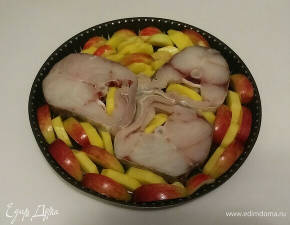 Смазать противень растительным маслом. Выложить стейки трески и между ними положить дольки картошки и яблок (кожурой вверх). Поставить противень в разогретую до 190°C духовку на 40 минут (время приготовления зависит от вашей духовки). За 10 минут до готовности добавить на противень репчатый лук.