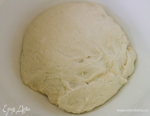 Замесить однородное тесто, переложить в чашу, смазанную маслом, накрыть полотенцем и убрать в теплое место на 40–60 минут. Когда тесто поднимется, его необходимо обмять и разделить на 2 части.