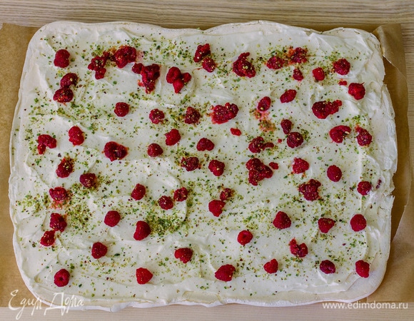 Готовый корж достать из духовки, сверху положить на него еще один лист пергамента и аккуратно перевернуть. Тот лист пергамента, на котором корж выпекался, теперь окажется сверху, его нужно снять. Дать меренге немного остыть (максимум 7–10 минут). Смазать кремом, выложить ягоды, посыпать орехами. Немного крема оставить для украшения.