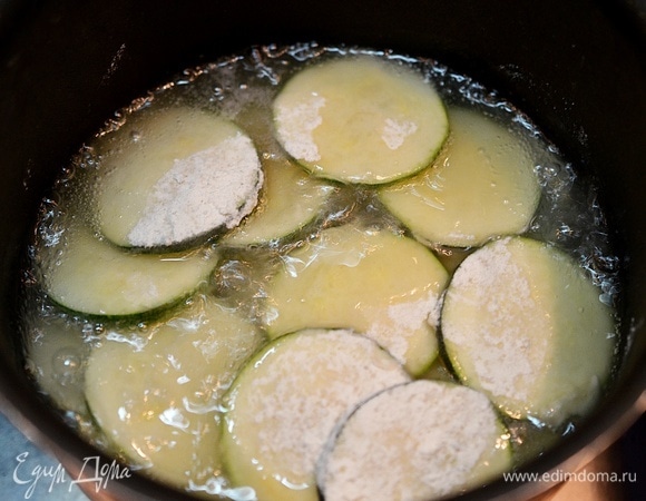 В сотейнике с толстым дном разогрейте растительное масло. Порциями (по 20–25 кружков) выкладывайте овощи.