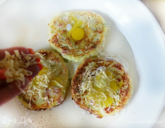 В сковороде разогрейте растительное масло. Выложите кабачковое тесто, сделайте с помощью чайной ложки небольшое углубление в центре, накройте крышкой и готовьте около 5 мин на небольшом огне. Затем переверните оладьи, в углубление вбейте перепелиное яйцо, посыпьте сыром, накройте крышкой и готовьте еще 3–5 мин.