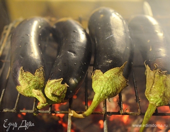 Баклажаны вымойте, наколите в нескольких местах вилкой и запеките на мангале или в духовке. Лучше на огне — это придаст блюду легкий аромат дымка.