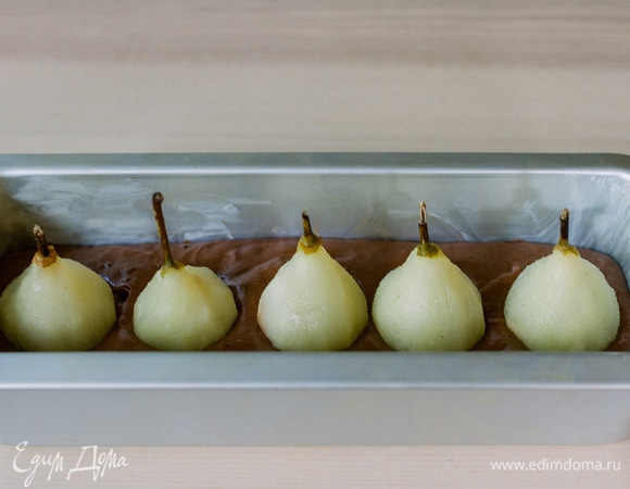 Форму смазать маслом и вылить в нее тесто, сверху выложить груши, очищенные от кожуры и проваренные в сиропе 10 минут (для сиропа 400 мл воды смешать с 70 г сахара).