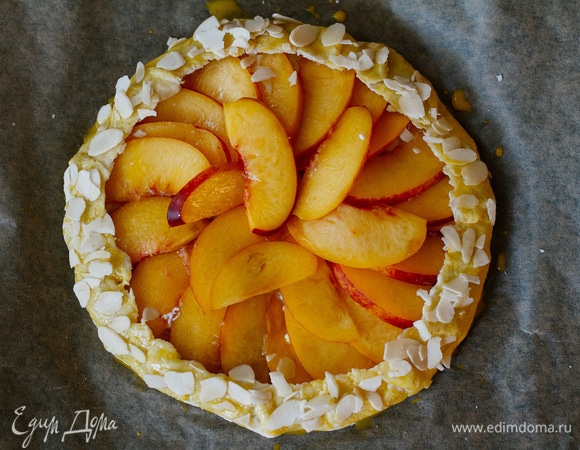 Края загнуть сверху на фрукты. Смазать желтком и посыпать миндальными лепестками. Повторить то же самое со второй частью теста.