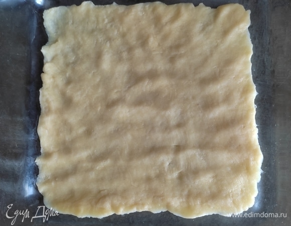 Форму для выпечки взять с высокими бортиками. У меня размер — 18х18 см. Раскатать тесто по размеру формы: три части одинаково, а одну на 1,5–2 см больше. Первый пласт теста выложить в форму.