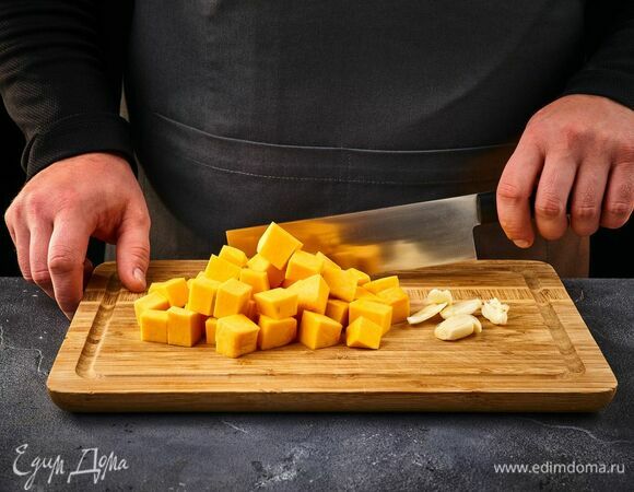 Тыкву очистите и нарежьте кубиками, чеснок раздавите. Выложите в чашку.