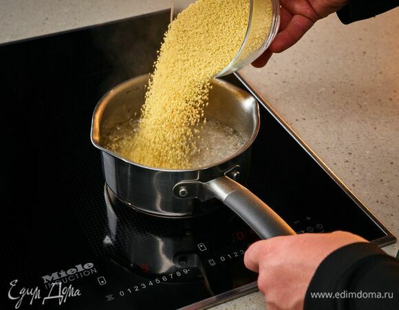 На панели конфорок Miele доведите воду до кипения на режиме Booster 2 (нажмите на уровень нагрева 9, держите, пока рядом с цифрой 9 не появится двоеточие). После закипания выключите, засыпьте кускус и оставьте настояться.