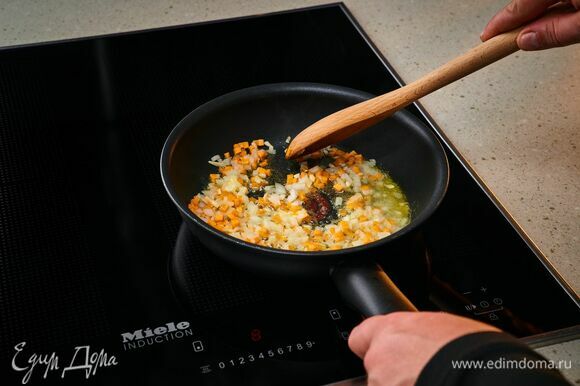 На индукционной панели конфорок Miele разогрейте сковороду со сливочным маслом. Обжарьте лук, чеснок, морковь, а затем переложите из сковороды в тарелку.