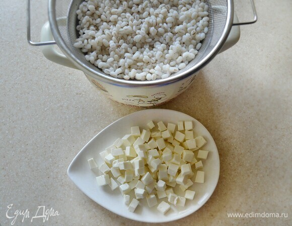 Перловую крупу промойте и отварите до готовности в слегка подсоленной воде. Слейте жидкость. Фетаксу нарежьте небольшими кубиками.