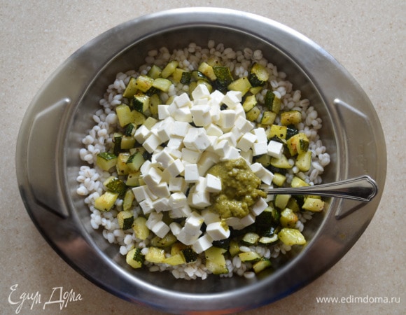 Смешайте в тарелке готовую перловую крупу, цукини, фетаксу. Добавьте соус песто и перемешайте.