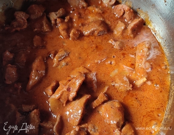 Вернуть мясо в кастрюлю к луку. Добавить паприку, лавровый лист и муку. Перемешать. Влить 200 мл воды, довести до кипения. Сделать огонь на минимум и тушить примерно 1 час под крышкой.