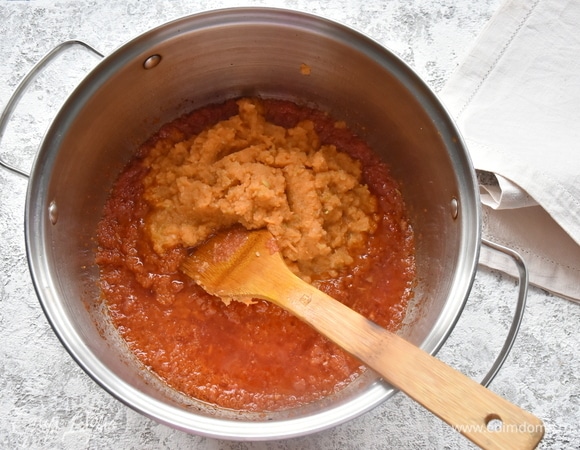 В кастрюле разогреваю растительное масло и добавляю массу из чеснока, лука и острого перца. Обжариваю, помешивая деревянной лопаткой, 3–5 минут. Добавляю пюре из моркови, яблока и томатной пасты. Обжариваю еще 2–3 минуты. Уменьшаю огонь и накрываю посуду крышкой.