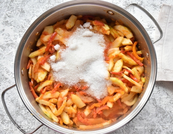 Подготовленные овощи отправляю в кастрюлю с соусом. Всыпаю соль и сахар, столовый уксус. Перемешиваю, накрываю посуду крышкой и тушу овощи на среднем огне в течение часа.
