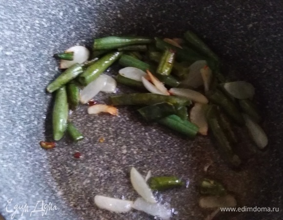 На растительном масле обжарить фасоль с добавлением нарезанного пластинами чеснока.
