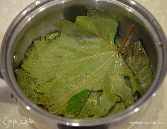 На дно сотейника для приготовления голубцов выложите внахлест виноградные листья.